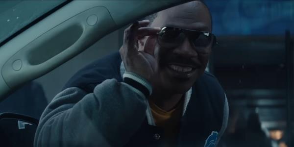 Eddie Murphy as Axel Foley smiles and holds his shades in Beverly Hills Cop: Axel F.